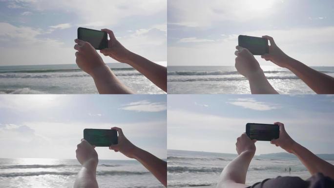 度假时，日落时在海边的海滩上用智能手机拍照。