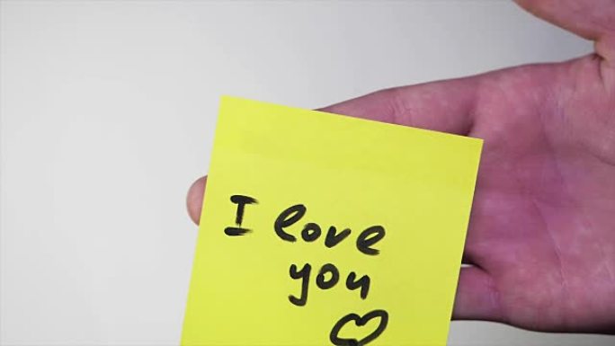 注意我爱你。空白的黄色便笺，上面写着 “我爱你” 在软木公告板上的标志。贴纸上的铭文我爱你在白色背景