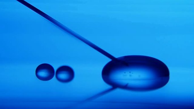 在医学实验室中，金属针从玻璃状表面浸泡晶体液体