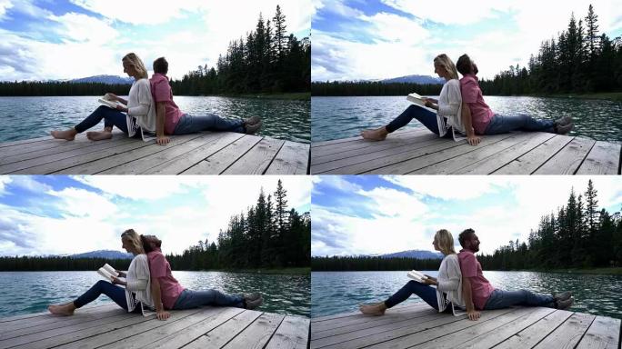 夫妇在加拿大背靠背坐在木制湖码头上放松