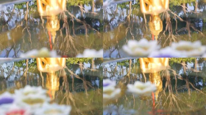 水中佛像的美丽金色倒影，上面漂浮着各种莲花形式的蜡蜡烛