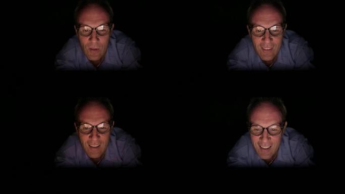 成熟的斯堪的纳维亚男子在黑暗的房间里用数字平板电脑观看成人视频