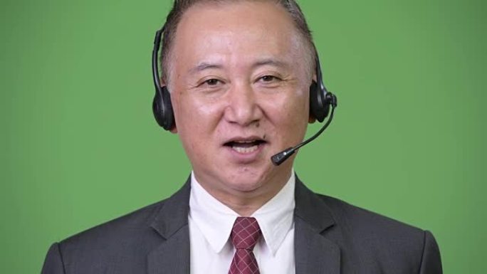 成熟的日本商人在绿色背景下担任呼叫中心代表