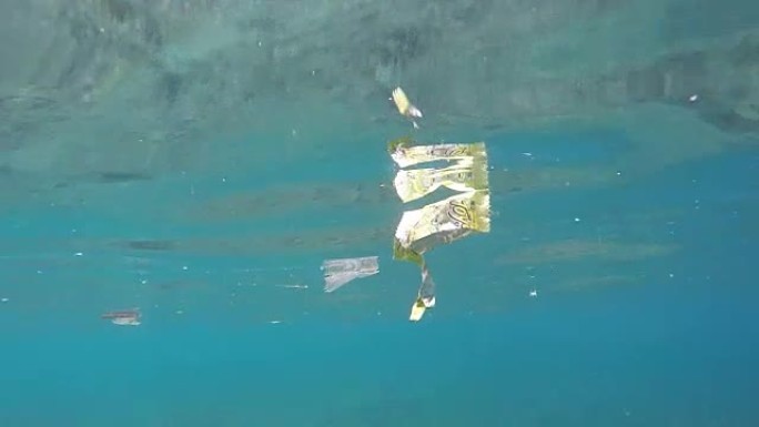 塑料垃圾和其他杂物漂浮在苏拉威西岛布纳肯岛脆弱的珊瑚礁上的水下