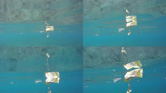 塑料垃圾和其他杂物漂浮在苏拉威西岛布纳肯岛脆弱的珊瑚礁上的水下