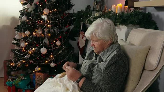 老年妇女在椅子上编织毯子