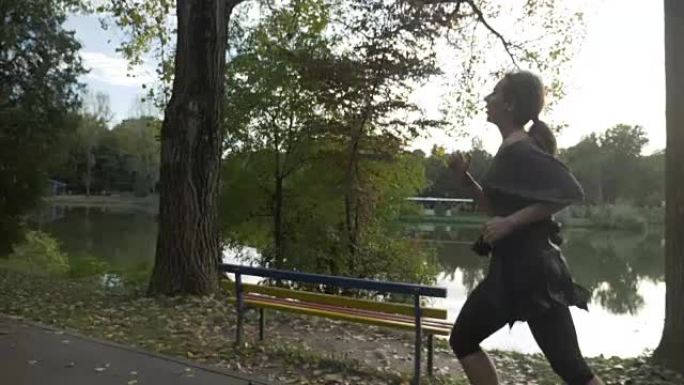 女孩与苗条的身材慢跑在一个小巷公园附近的湖，试图放松和保持动机在慢动作