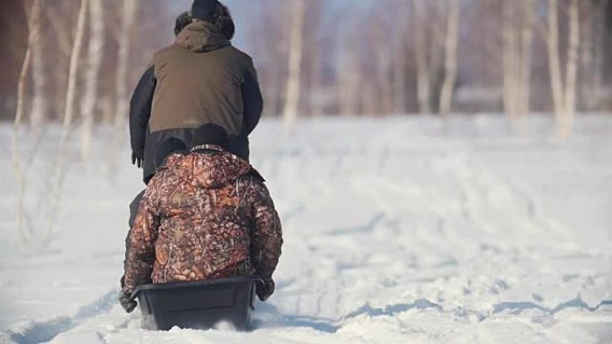 三名穿着冬装的男子骑着一辆带拖车的迷你雪地车穿越冬季场地