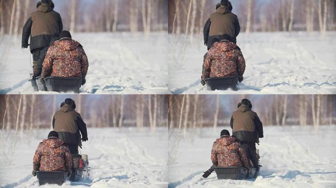 三名穿着冬装的男子骑着一辆带拖车的迷你雪地车穿越冬季场地