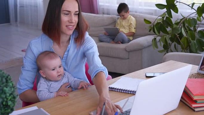 母亲带着孩子在客厅用笔记本电脑工作