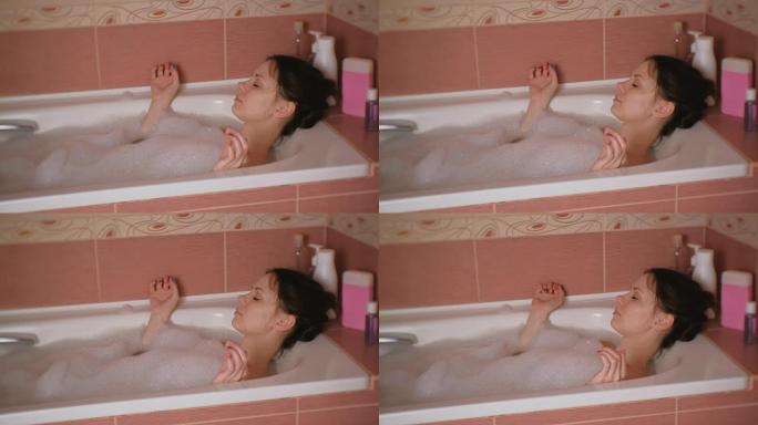 年轻漂亮的女人一边用泡沫洗澡一边休息。