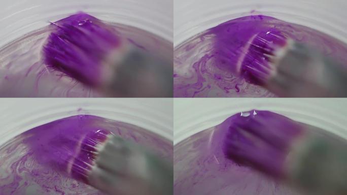 将紫色颜料浸入水玻璃中的画笔