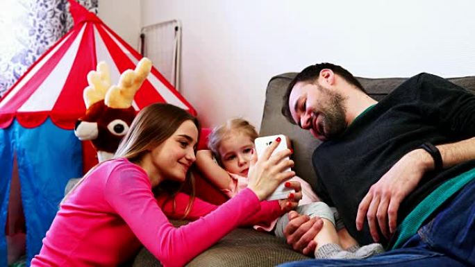家庭母亲父亲和女儿看着智能手机