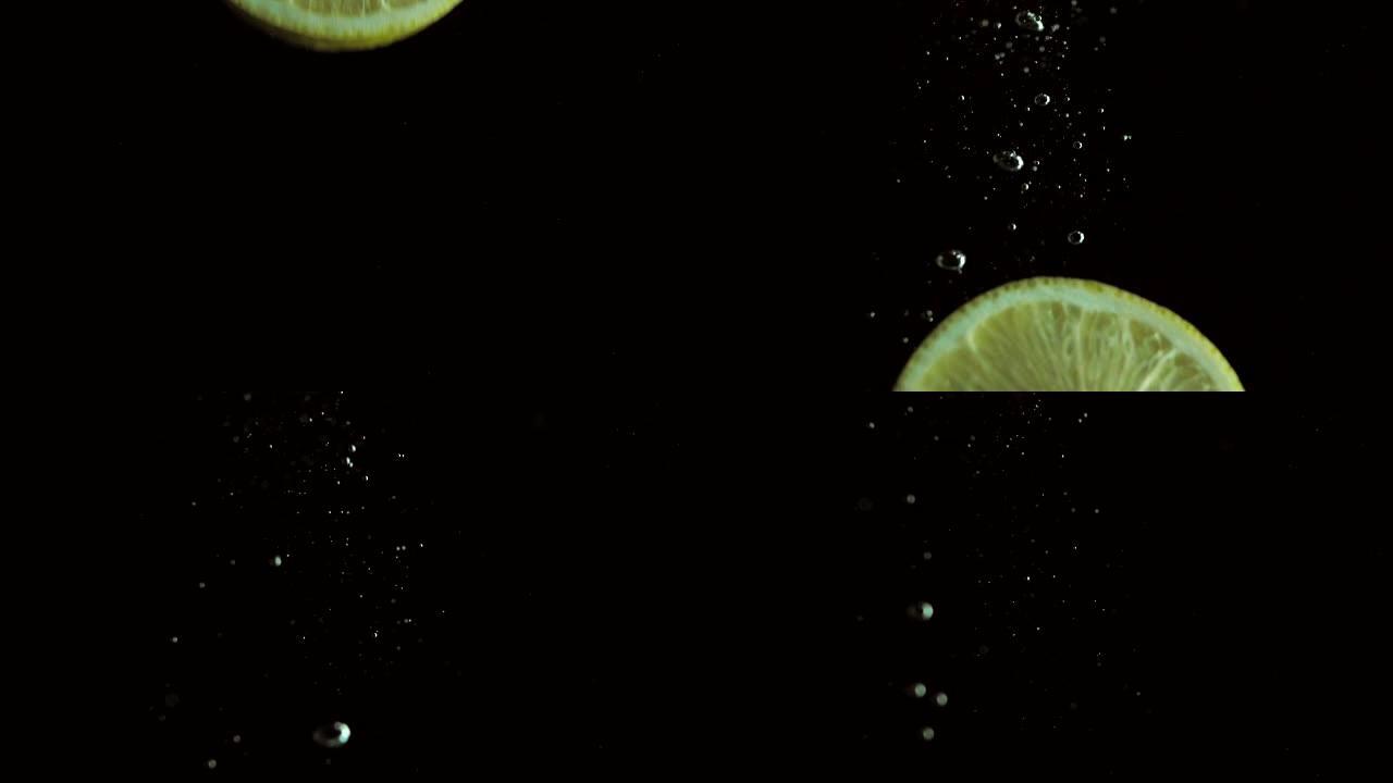 圆形新鲜多汁的柠檬片浸入透明的水中，并带有爆炸性的惊人飞溅，破坏了液体的表面。在黑色背景上拍摄的水下
