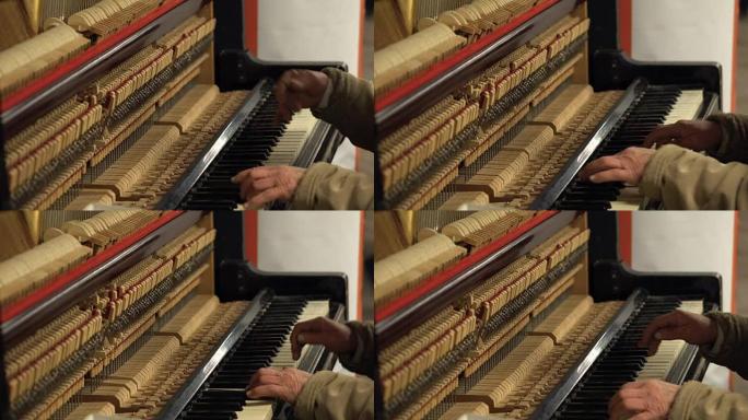 地铁地下老人的手用打开的琴弦和锤子弹奏钢琴
