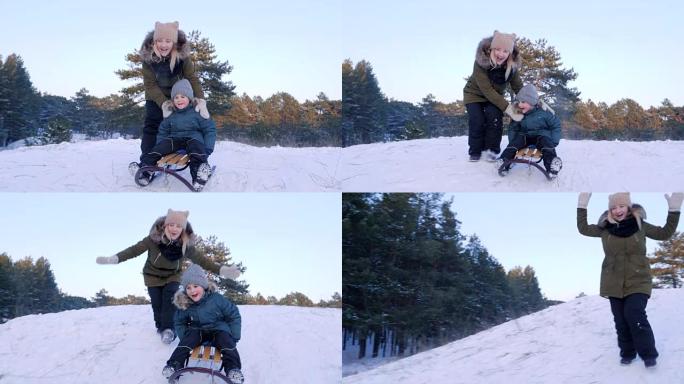 冬日，快乐的年轻女子将儿子从雪山推上雪橇，以慢动作追赶他