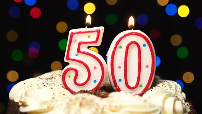 蛋糕上的50号-五十岁生日蜡烛燃烧-最后吹灭。彩色模糊背景