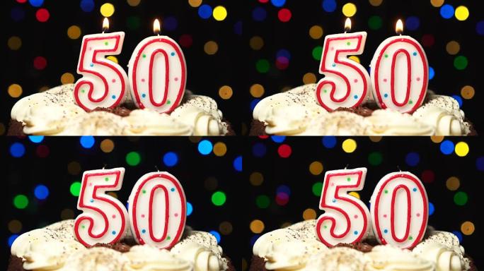 蛋糕上的50号-五十岁生日蜡烛燃烧-最后吹灭。彩色模糊背景