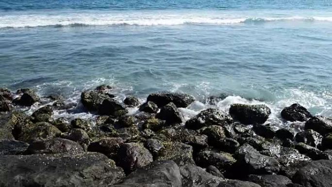 巨浪击中岩石。波浪撞击热带海滩上的岩石，形成飞溅的形状。岩石海滩上强大的波浪。