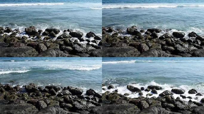 巨浪击中岩石。波浪撞击热带海滩上的岩石，形成飞溅的形状。岩石海滩上强大的波浪。