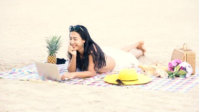 女人在海滩上放松，女人在笔记本电脑上玩社交媒体