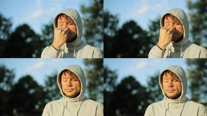 练习调息法的人特写慢动作。呼吸控制按压鼻孔在户外清洁鼻子在大自然阳光开明。阳光公园的连帽瑜伽训练替代