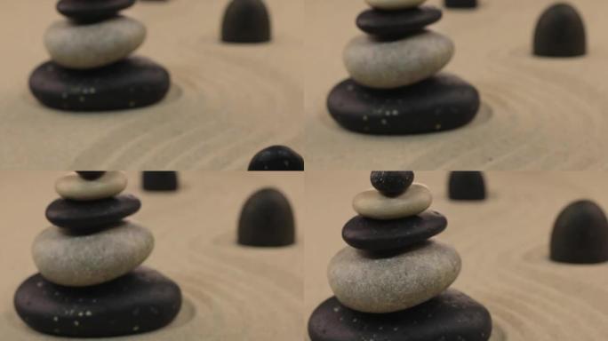 走近站在曲折沙地上的石头和黑色石头制成的金字塔