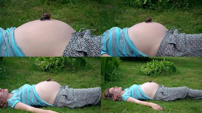 放松的孕妇躺在草地上，大蜗牛在肚子上爬行