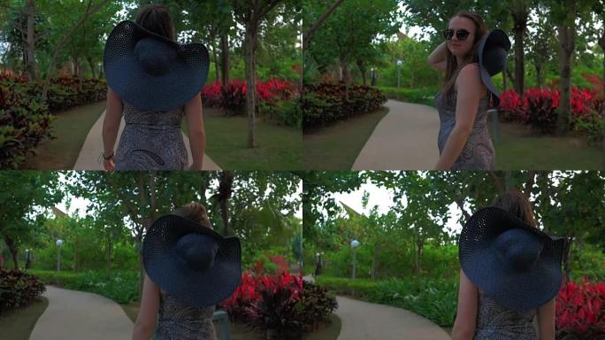 戴着蓝帽子的年轻女孩正穿过一个热带公园。夏天的时候。慢动作。