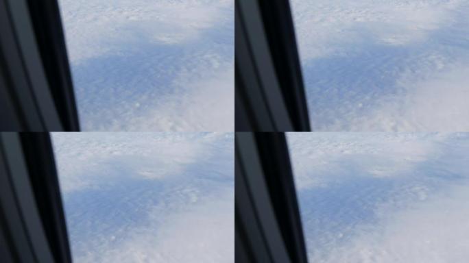 飞机的机翼穿过舷窗。飞机飞过美丽的空中云层