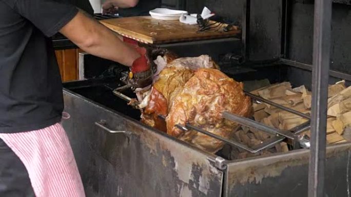 在明火上方的吐口水上准备的大块肉烤猪腿。捷克共和国布拉格的街头美食