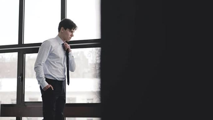 Handsome thoughtful man stands and looks at window