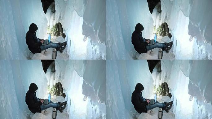 黑客入侵了服务器。男人在冰洞的笔记本电脑上编程。在神秘的冰窟周围。人把自己藏在兜帽里。黑客在互联网上