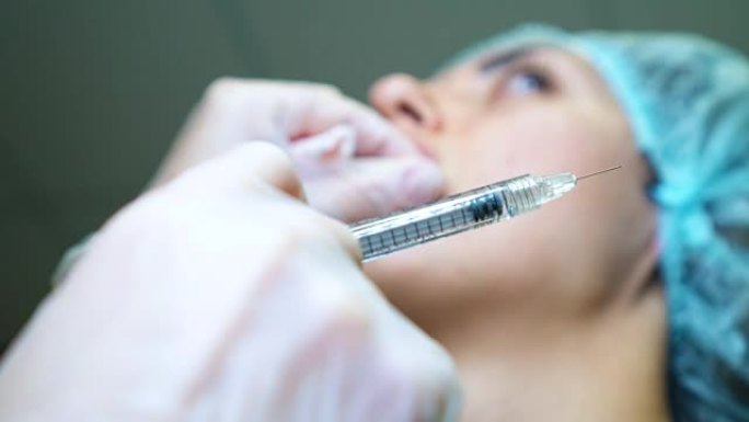 美容师制作注射塑料嘴唇。诊所的年轻女子嘴唇增大