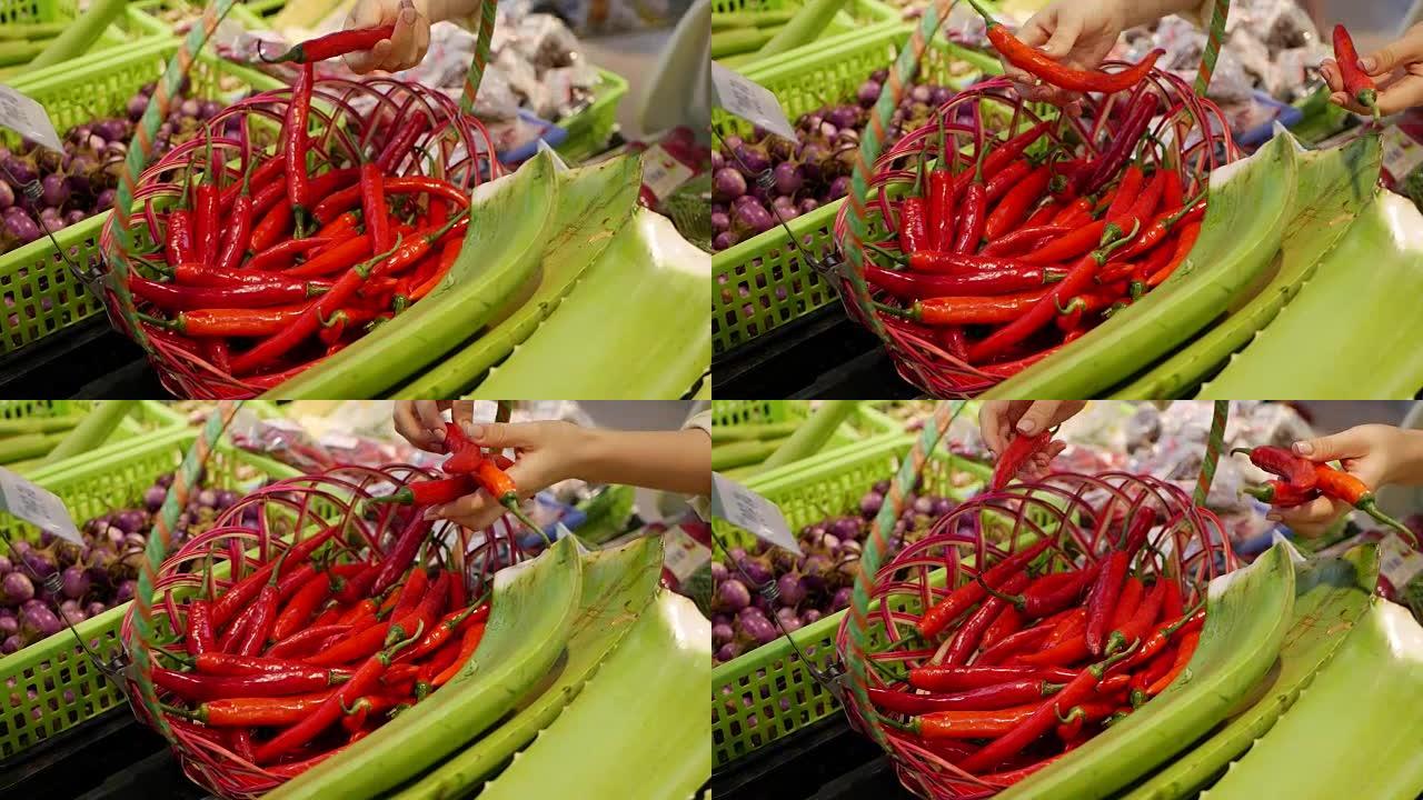 女性在商店里挑选和拿着红辣椒。年轻女子在超市的模糊背景下购买健康食品