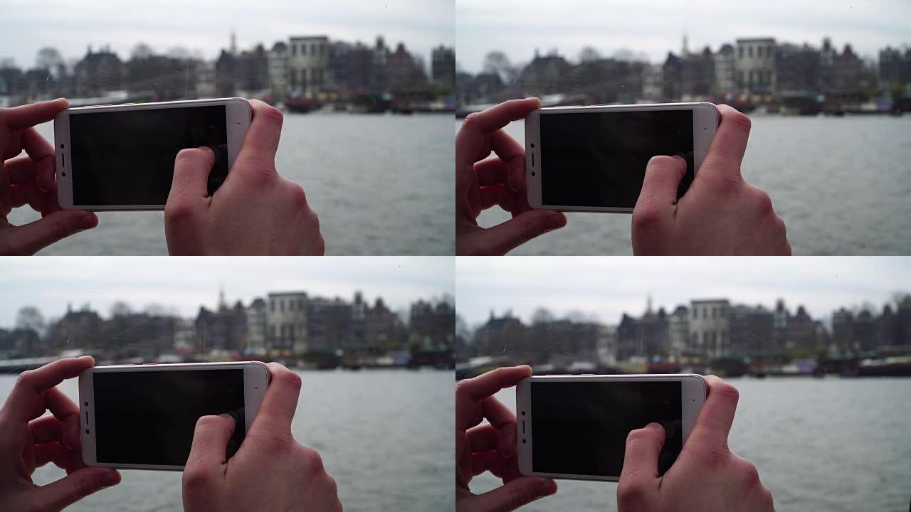 女孩乘船穿越阿姆斯特丹的运河，并在电话上拍照