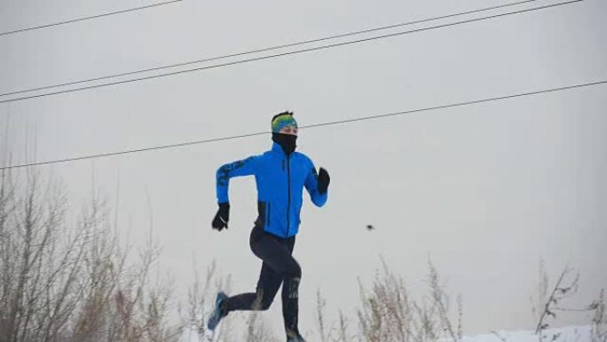 年轻的男运动员在冬天穿过雪地跑得很快