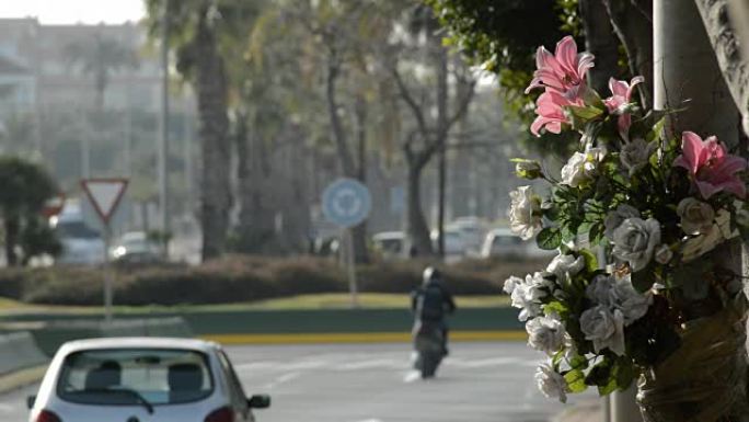 路灯中的花朵，以纪念交通事故，汽车在路上行驶