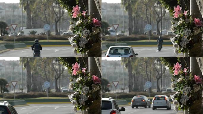 路灯中的花朵，以纪念交通事故，汽车在路上行驶