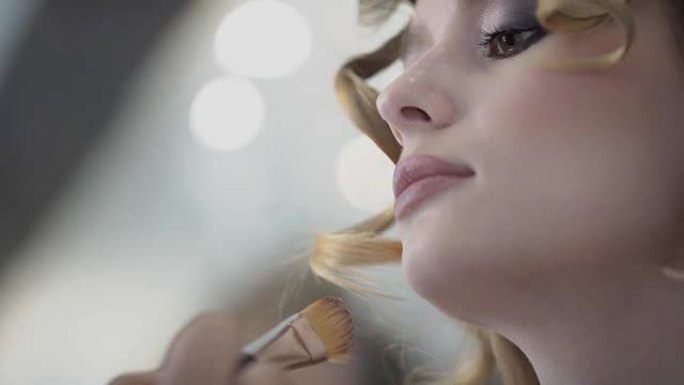 女人用刷子在脸上铺设头发和化妆的特写镜头