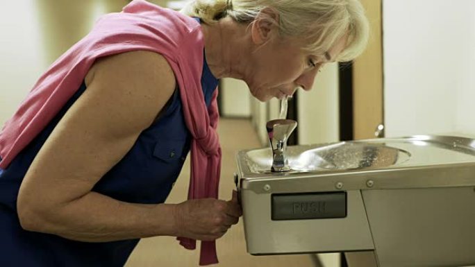 女商人从饮水机中喝水