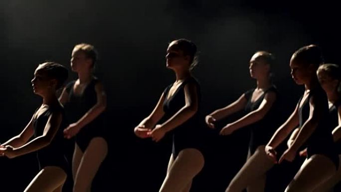 一群芭蕾舞演员在黑暗中的舞台上跳舞