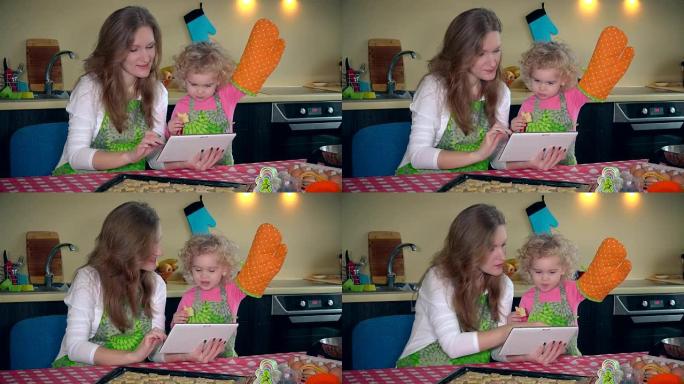 妈妈带着可爱的小女儿女孩在平板电脑上学习饼干食谱