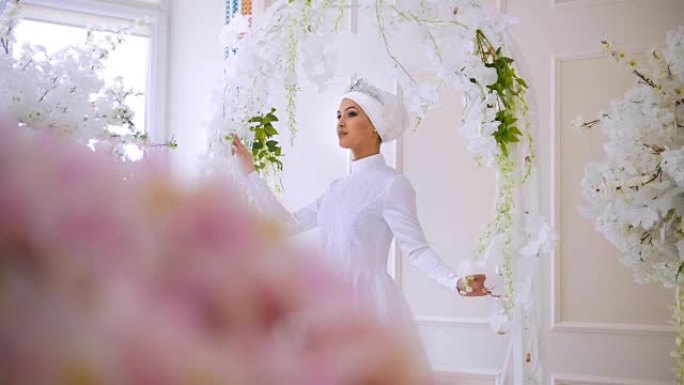 穿着白色婚纱的美丽穆斯林模特，穆斯林头饰在工作室摆姿势