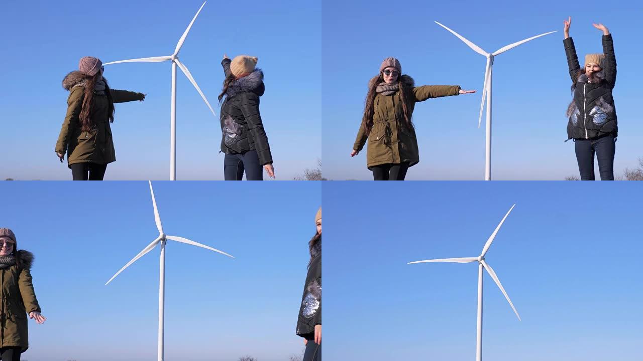 能量转换，开朗的朋友在蓝天下的风力发电机附近玩得开心