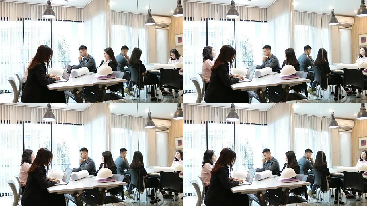 亚洲商人和工程师小组使用笔记本为商业伙伴在会议上讨论文件和想法，商业女性为工作而微笑
