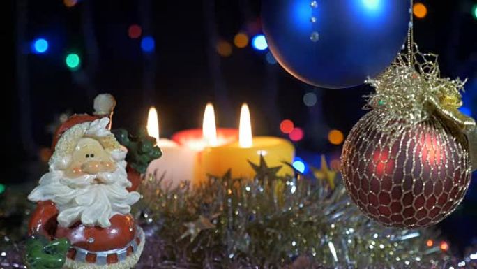 新年和圣诞装饰品。燃烧蜡烛。闪光花环。背景模糊。一个美丽的红球。圣诞老人。