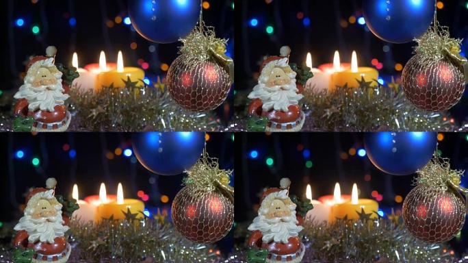 新年和圣诞装饰品。燃烧蜡烛。闪光花环。背景模糊。一个美丽的红球。圣诞老人。