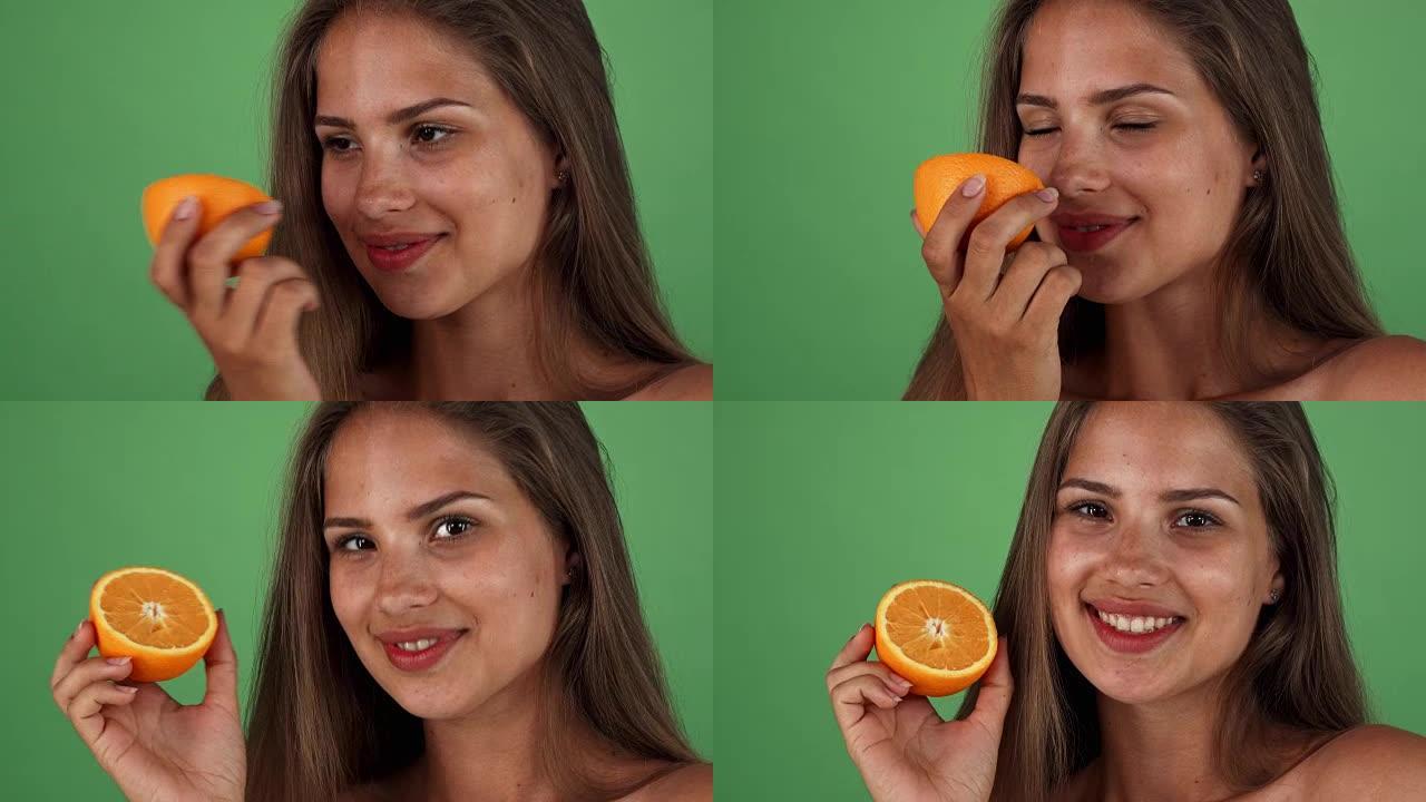幸福美丽的女人开心地笑着，手里拿着一个橙子
