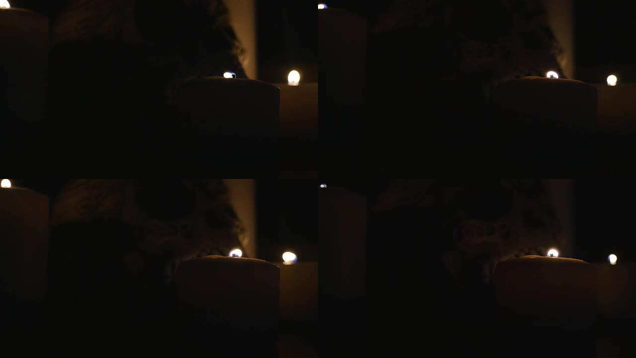 四个点燃的蜡烛和一个黑色背景上的头骨。特写